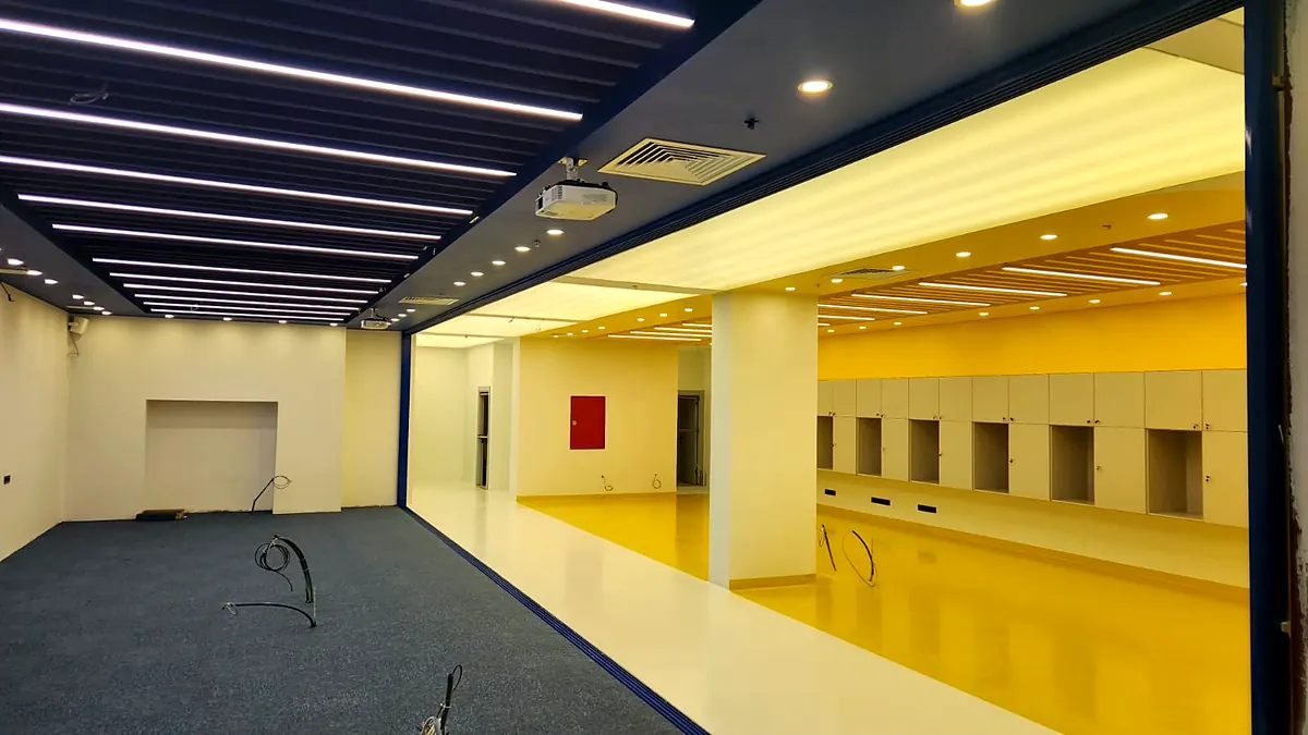 TED Üniversitesi Teacher+ laboratuvarı: lineer tavan aydınlatmaları ve sarı zeminli çalışma alanı